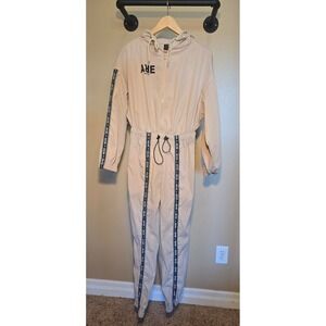 Tan hooded jumpsuit with a partial zip and "never ever" words throughout
